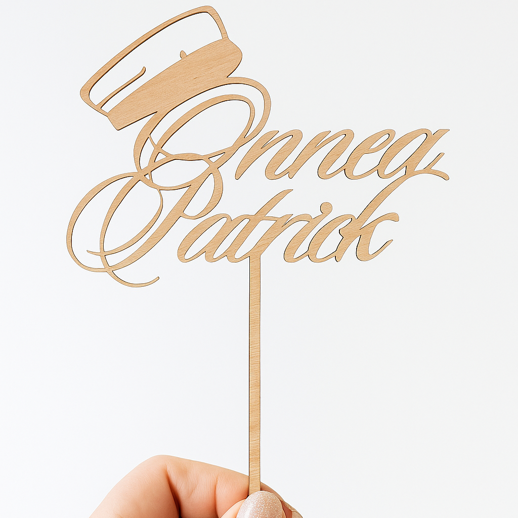 Koivuvanerinen ylioppilaslakki-kakkukoriste, jossa teksti "Onnea Patrick" kahdella rivillä, valkoista taustaa vasten.